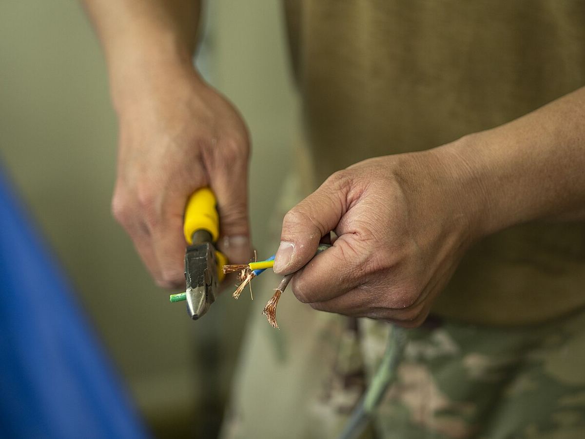 Close-up of a technician stripping electrical wires with pliers